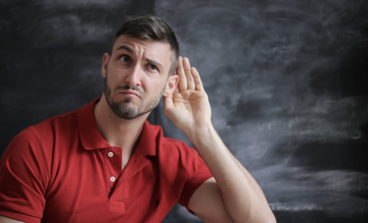 Person with hand cupped over one ear.